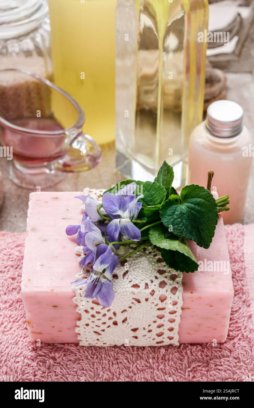 Barretta rosa di sapone naturale fatto a mano e piccolo bouquet di violette. Tempo per il centro benessere Foto Stock
