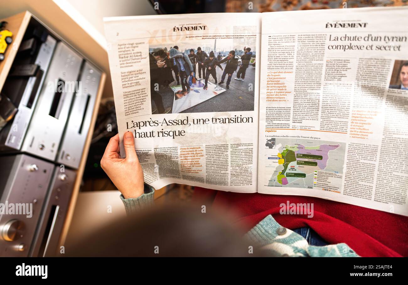 Parigi, Francia - 9 dicembre 2024: Un articolo di giornale che analizza le sfide post-Assad in Siria, tenuto aperto da una persona, con mappe e rapporti di accompagnamento Foto Stock