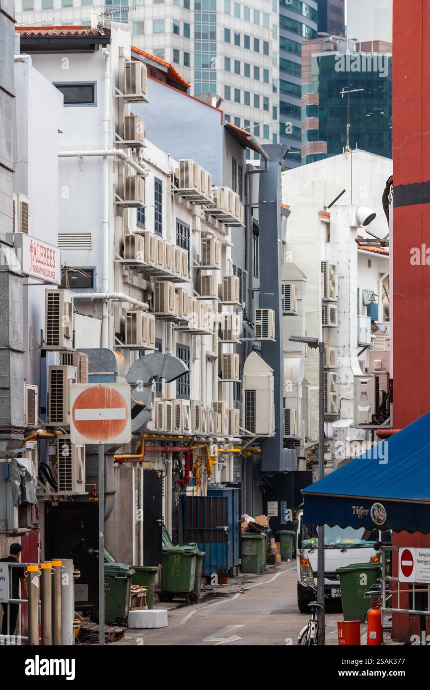 Vista tipica su una strada laterale stretta di Singapore, dove gli edifici sono pieni di condizionatori d'aria per tenere fuori il calore tropicale e l'umidità Foto Stock