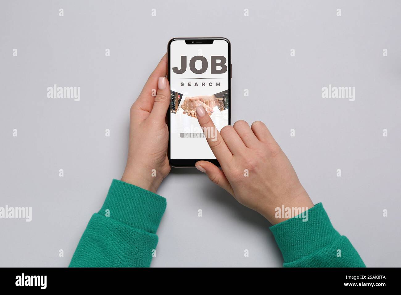 Ricerca di un lavoro. Donna che utilizza il sito Web per l'impiego sul cellulare al tavolo grigio, vista dall'alto Foto Stock