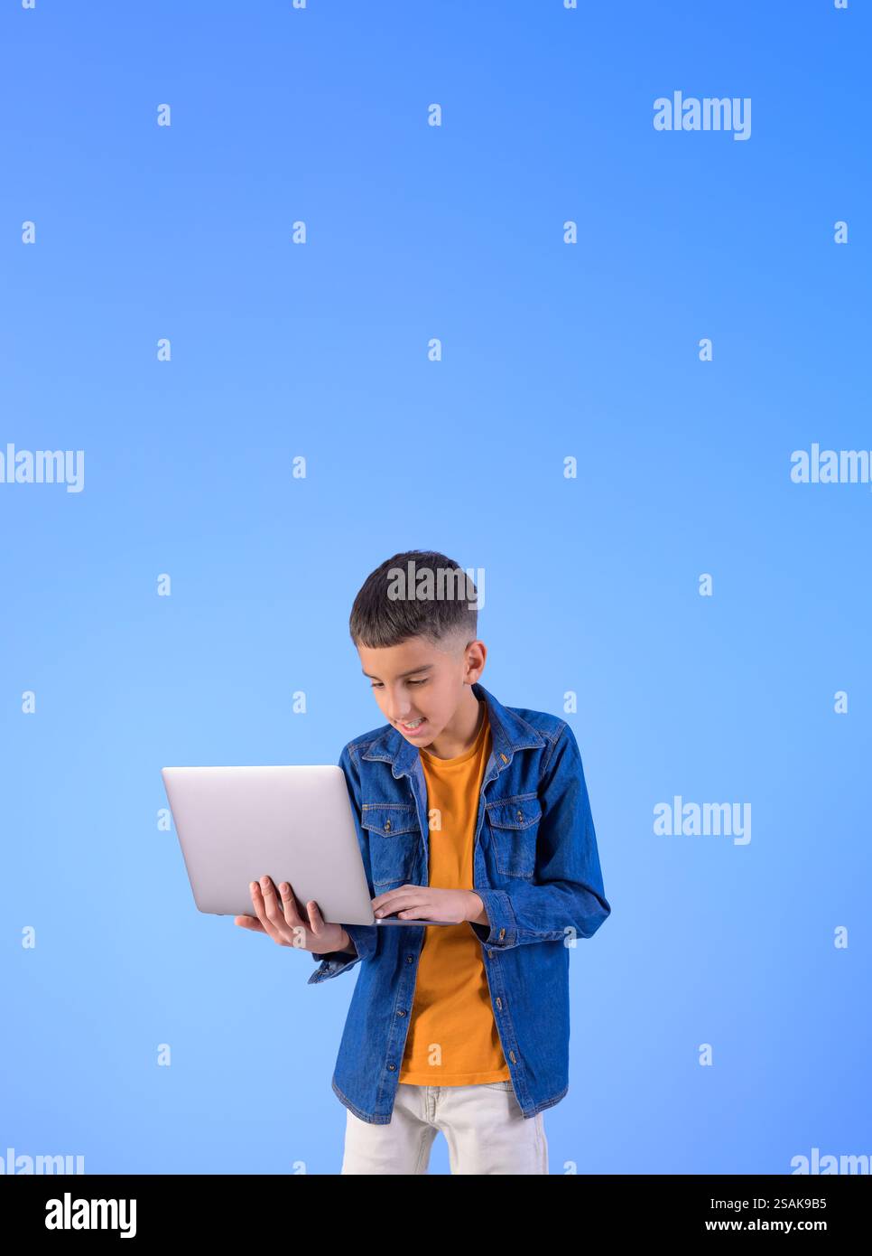 Ritratto di un giovane piccolo manager che lavora online su un notebook mentre si trova su uno sfondo blu isolato Foto Stock