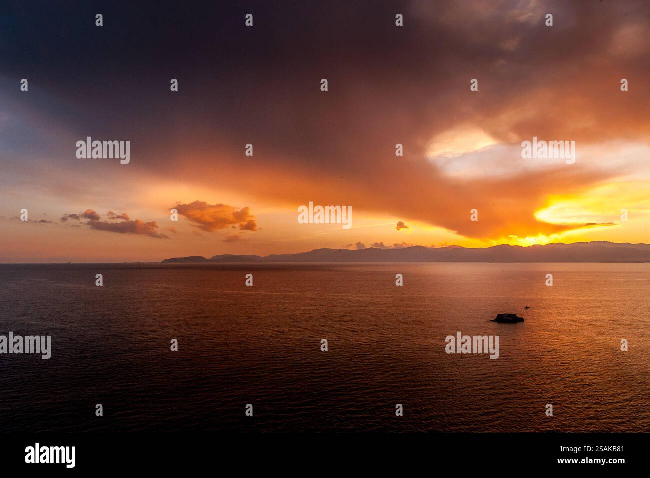 Spettacolare tramonto sul Mar Mediterraneo a Golfo degli Angeli vicino a Cagliari, in Sardegna, con cielo colorato e nuvole che si riflettono sull'acqua. Foto Stock