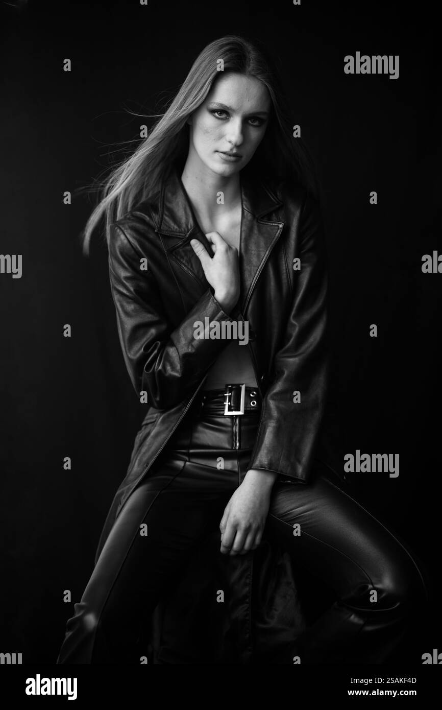 Intensità senza tempo - ritratto in bianco e nero di donna in pelle, seduta con una posa forte, il suo sguardo intenso irradia potenza e sicurezza, contras Foto Stock