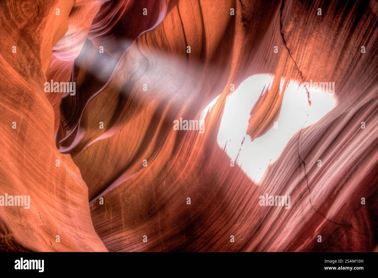 Un profondo canyon con un'ombra bianca gettata sul muro. Il canyon è pieno di rocce arancioni e la luce del sole splende attraverso lo spazio tra le rocce, c Foto Stock