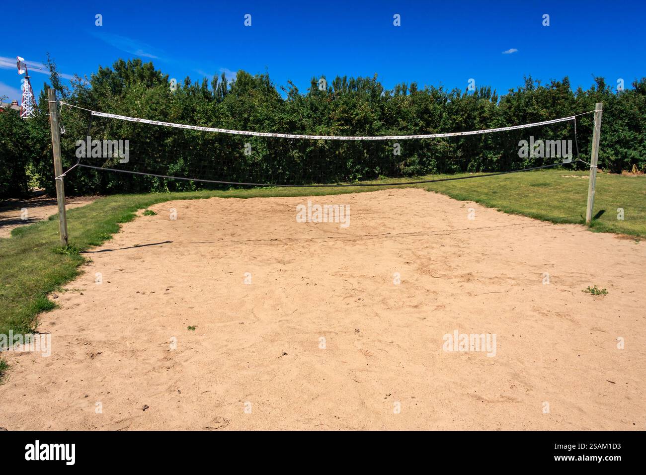 Una rete da pallavolo viene allestita in un campo con un cielo blu sullo sfondo. La rete è bianca ed è estesa attraverso il campo Foto Stock