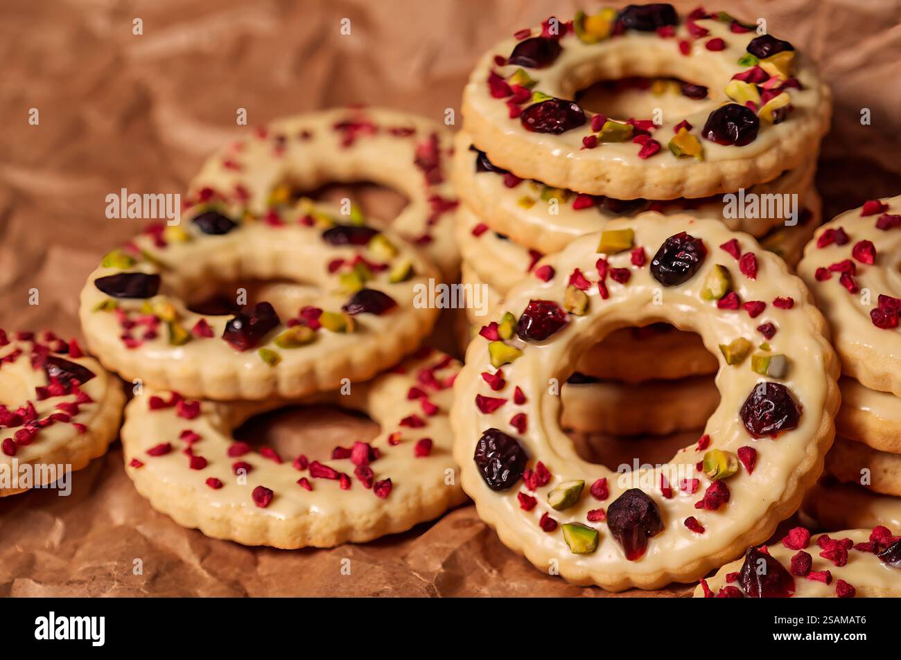 Biscotti di Natale decorati con smalto bianco, mirtilli rossi e pistacchi da vicino. I tradizionali biscotti per le vacanze hanno un aspetto moderno grazie all'elegante de Foto Stock