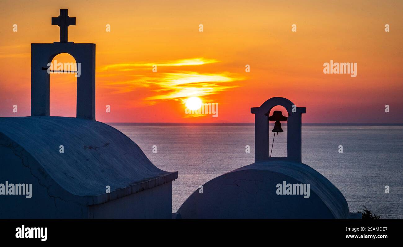 Uno splendido tramonto sul mare, caratterizzato da cupole e campanili sagomati. Il cielo è dipinto in vivaci tonalità di arancione, giallo e viola, Foto Stock