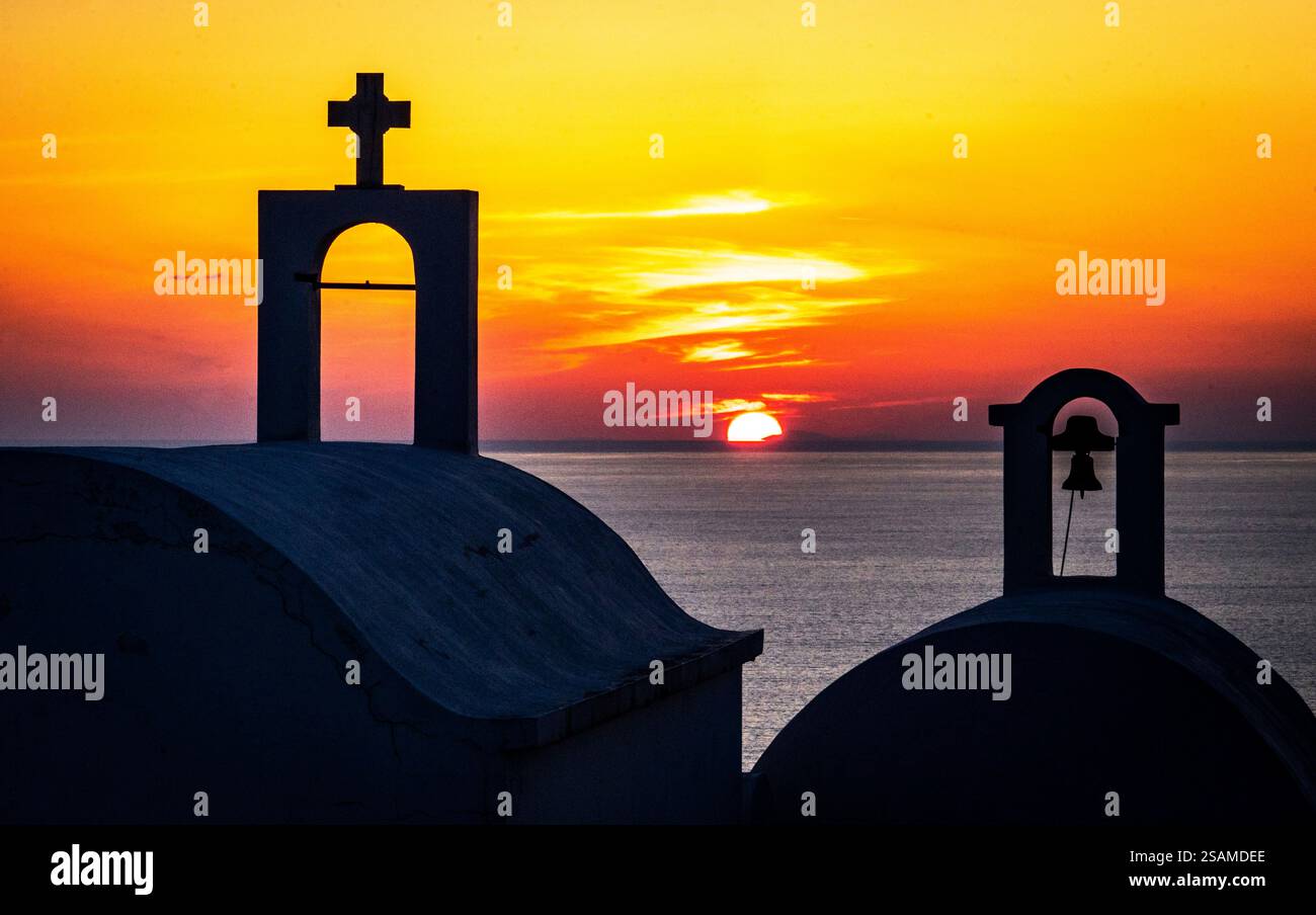 Uno splendido tramonto sull'oceano, incorniciato dalle sagome delle cupole e delle croci della chiesa. Il cielo è dipinto in vibranti tonalità di arancione e giallo, cr Foto Stock