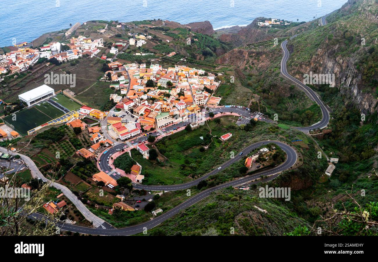 Vista aerea di un villaggio costiero con strade tortuose e campi terrazzati. Il villaggio presenta case colorate ed e' circondato da lussureggianti colline verdi Foto Stock