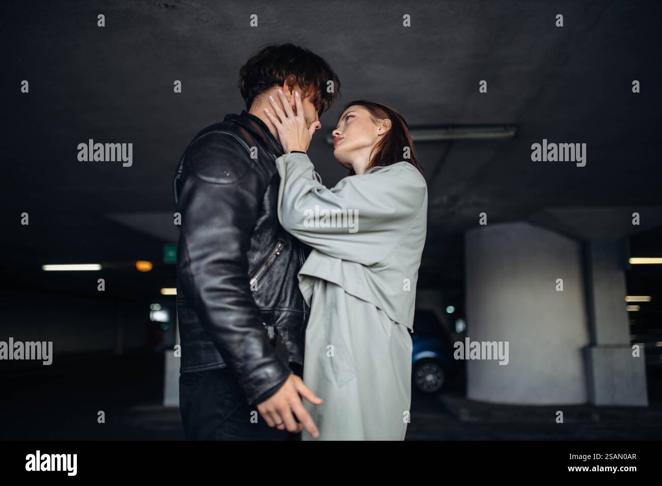 La donna tocca delicatamente il volto dell'uomo, mostrando tenerezza in un parcheggio Foto Stock
