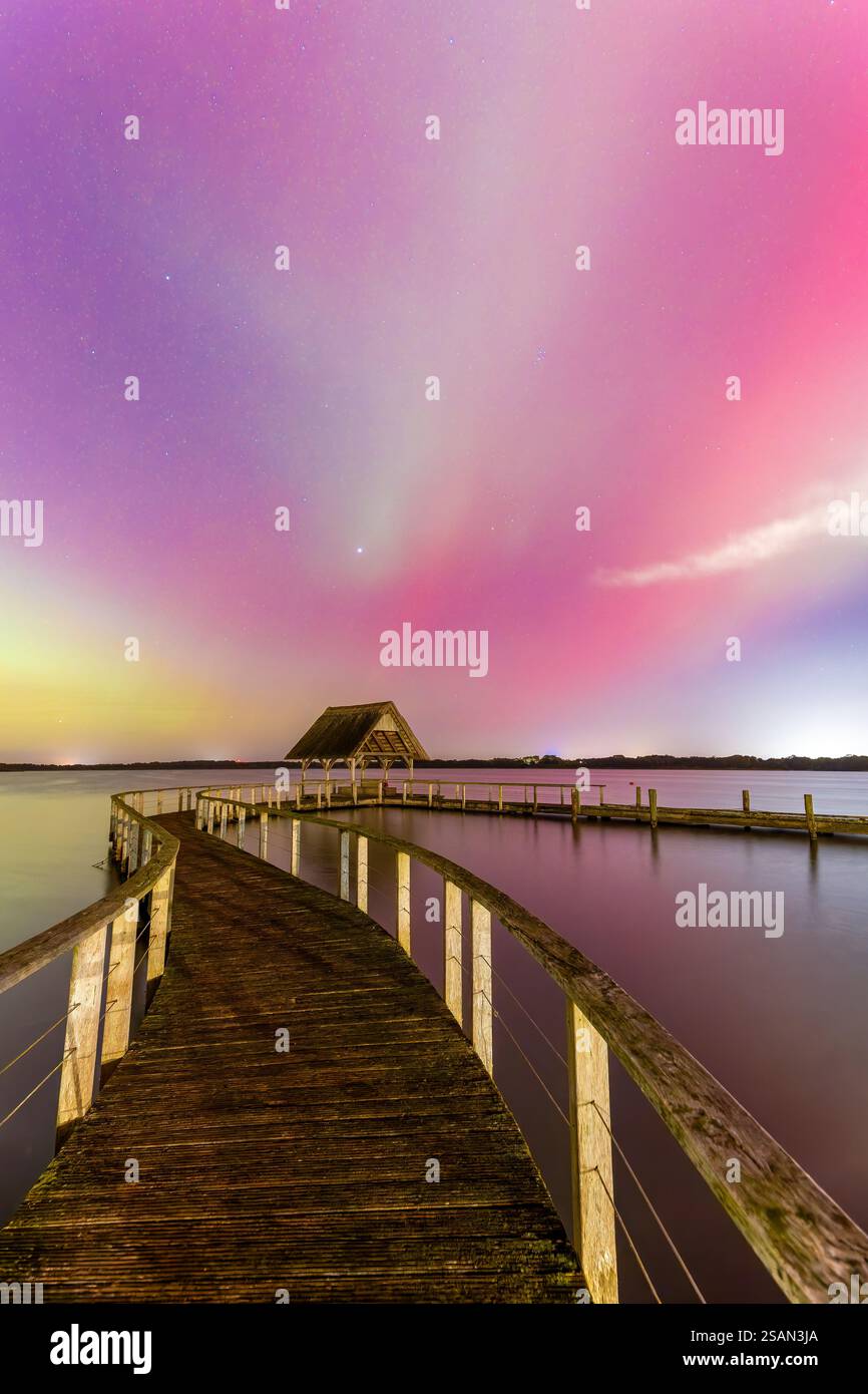 Molo in legno e aurora boreale / luci polari sul lago Hemmelsdorf / Hemmelsdorfer SEE vicino a Lübeck, Schleswig-Holstein, Germania Foto Stock
