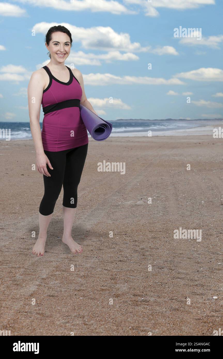 Bella donna che porta con sé un tappetino da yoga prima di fare esercizio fisico Foto Stock