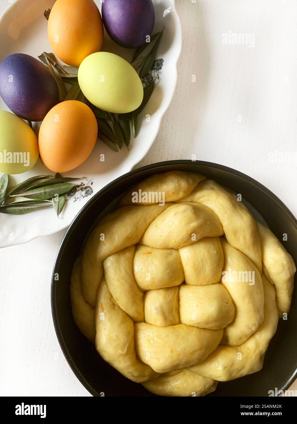 Pane dolce di Pasqua, cozonac o tsoureki e uova di Pasqua colorate su un tavolo di legno bianco. Brioche intrecciate, dolce tradizionale natalizio. Vacanze di Pasqua. Foto Stock