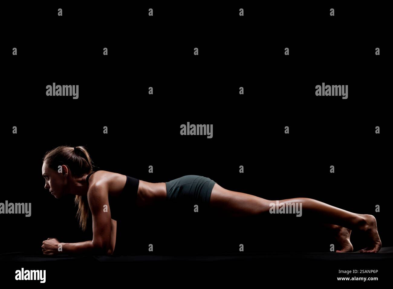 Mostra fitness di una donna che si mette in posa. Black Backdrop enfatizza il suo atletismo e la sua dedizione all'esercizio fisico e al benessere fisico. Foto Stock