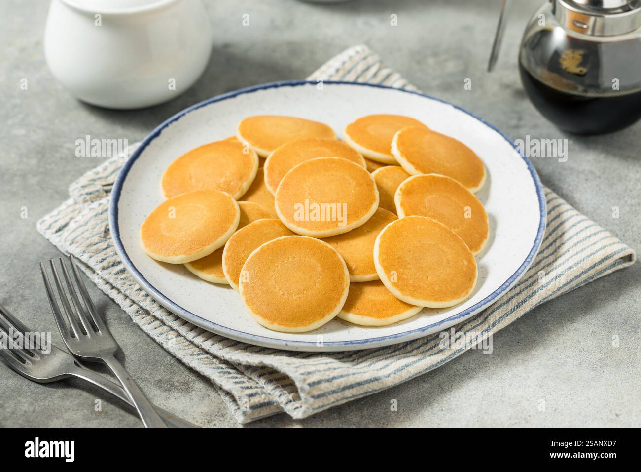 Mini pancake fatti in casa a forma di dollaro d'argento per colazione con burro e sciroppo Foto Stock