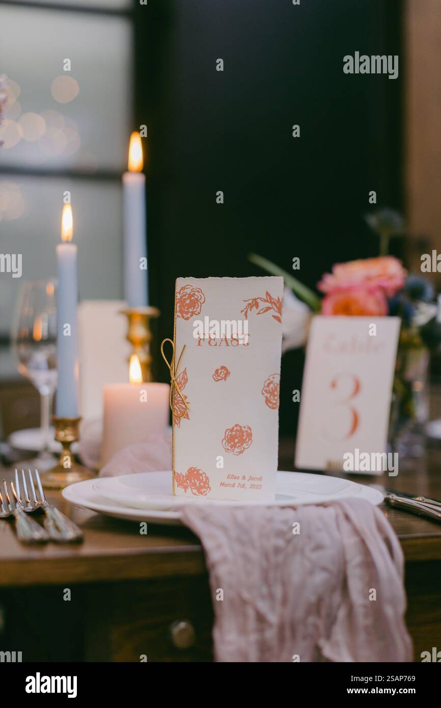 Un tavolo da pranzo splendidamente allestito presenta un menu di festa circondato da candele, fiori e raffinati utensili da pranzo, creando un'atmosfera invitante Foto Stock