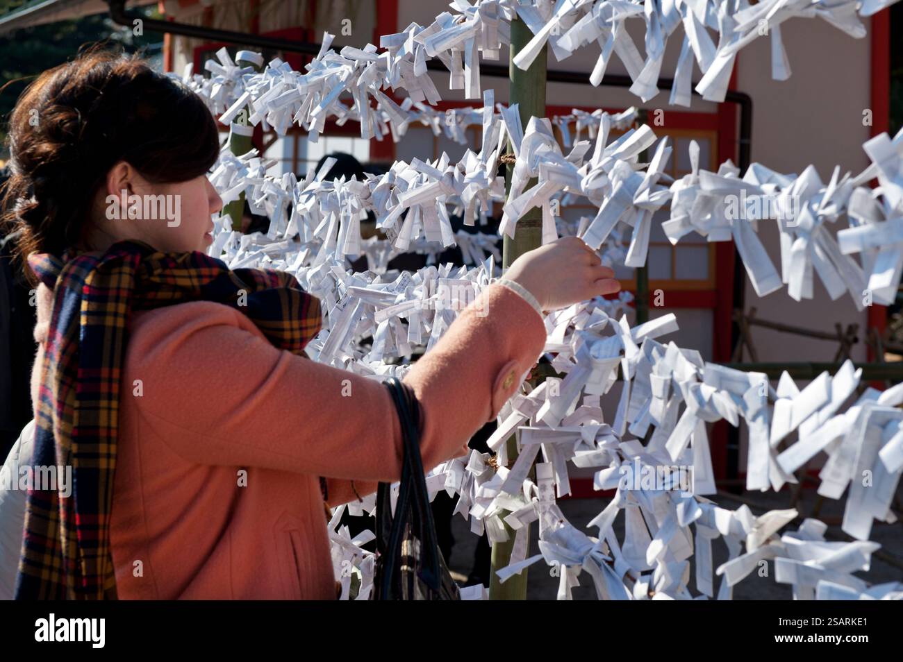Persone che legano il loro "omikuji" (oracolo di carta di buona o cattiva sorte) a una stringa durante la "Hatsumode" (visita al santuario di Capodanno) a Heian Jingu a Kyoto, Giappone. Foto Stock