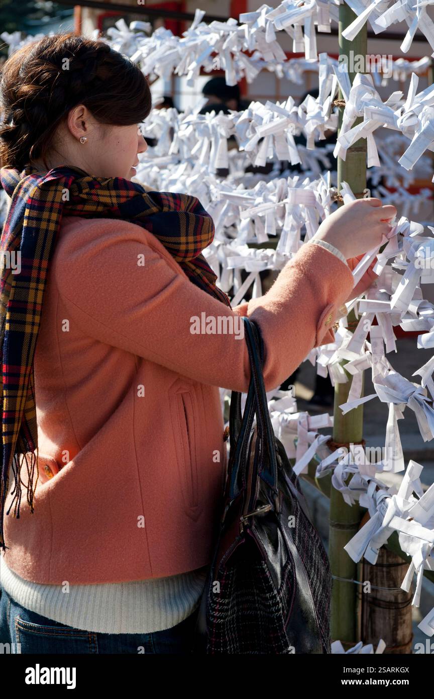 Persone che legano il loro "omikuji" (oracolo di carta di buona o cattiva sorte) a una stringa durante la "Hatsumode" (visita al santuario di Capodanno) a Heian Jingu a Kyoto, Giappone. Foto Stock