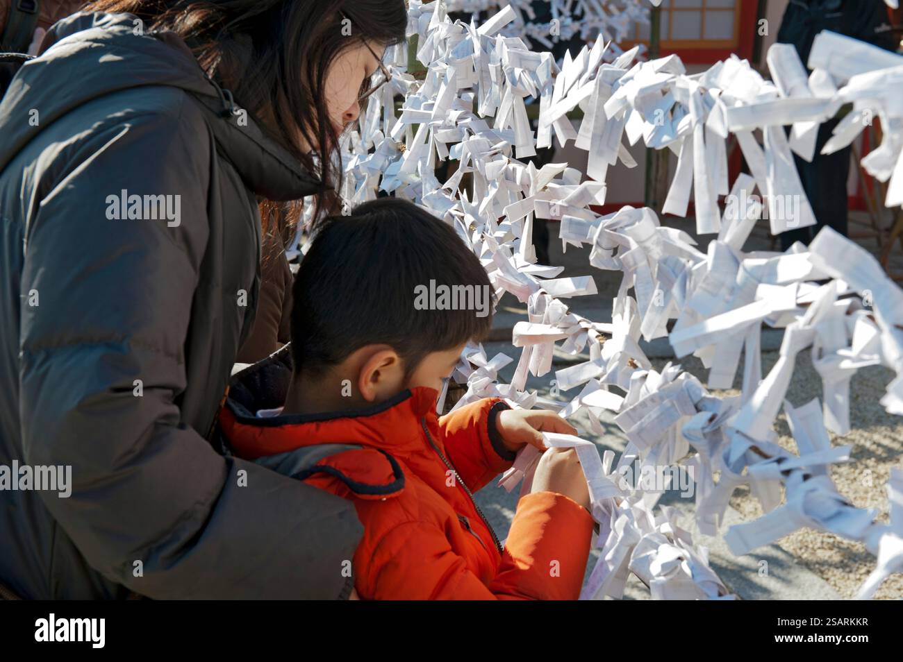 Persone che legano il loro "omikuji" (oracolo di carta di buona o cattiva sorte) a una stringa durante la "Hatsumode" (visita al santuario di Capodanno) a Heian Jingu a Kyoto, Giappone. Foto Stock