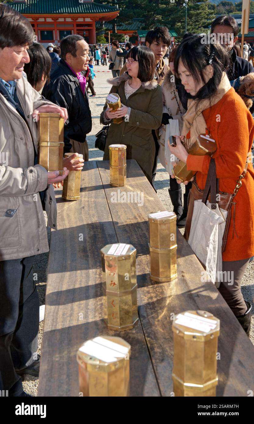 Persone che selezionano un numero da una tanica metallica "omikuji" (oracolo) durante la "Hatsumode" (visita al santuario di Capodanno) augurando buona fortuna a Heian Jingu. Foto Stock