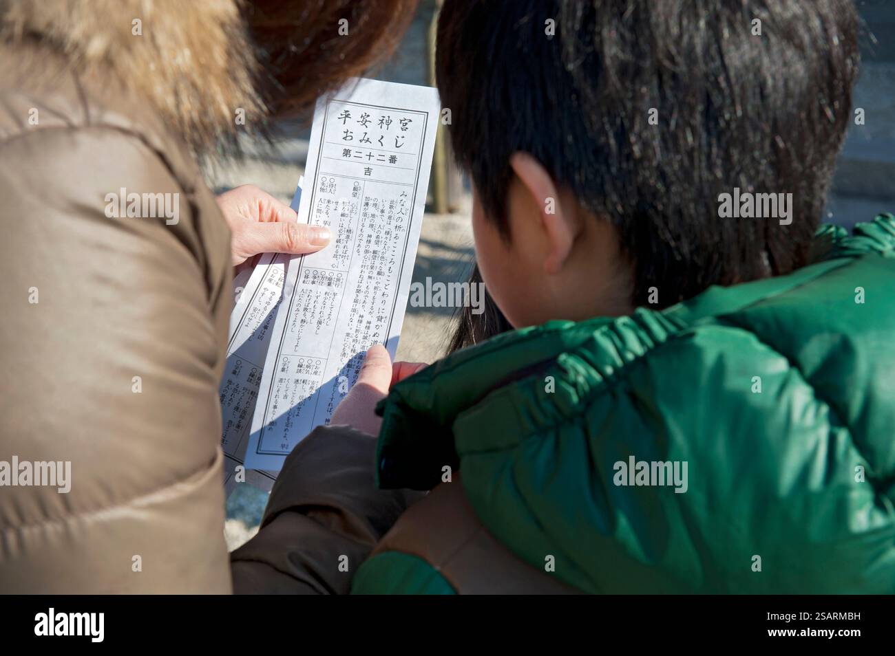 Persone che leggono il loro "omikuji" (oracolo di buona o cattiva sorte) durante la "Hatsumode" (visita al santuario di Capodanno) al santuario shintoista Heian Jingu a Kyoto, in Giappone Foto Stock