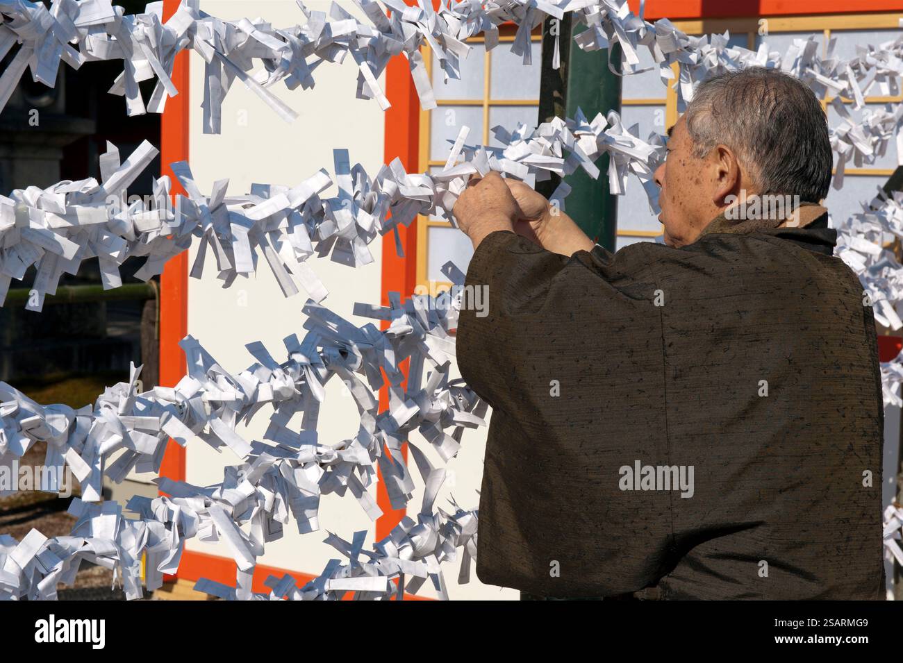 Persone che legano il loro "omikuji" (oracolo di carta di buona o cattiva sorte) a una stringa durante la "Hatsumode" (visita al santuario di Capodanno) a Heian Jingu a Kyoto, Giappone. Foto Stock