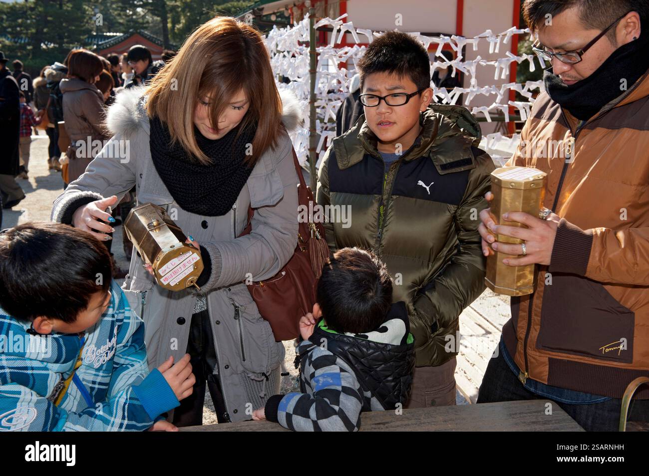 Persone che selezionano un numero da una tanica metallica "omikuji" (oracolo) durante la "Hatsumode" (visita al santuario di Capodanno) augurando buona fortuna a Heian Jingu. Foto Stock