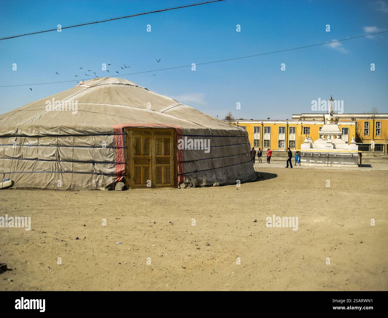 Una tenda è nel mezzo di un deserto. La tenda è ricoperta di materiale bianco. Ci sono diverse persone che camminano intorno alla tenda Foto Stock