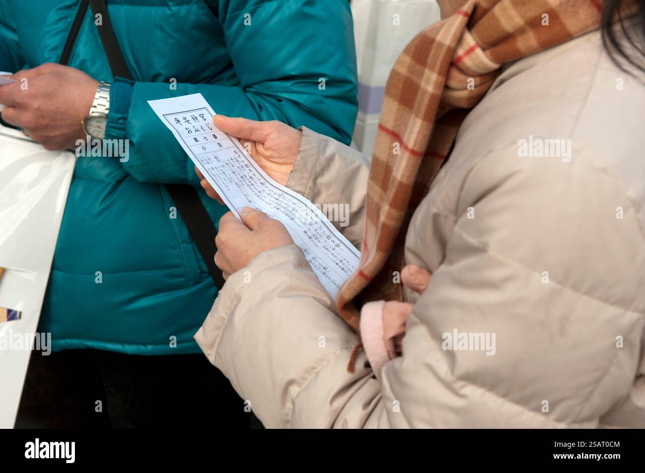 Persone che leggono il loro "omikuji" (oracolo di buona o cattiva sorte) durante la "Hatsumode" (visita al santuario di Capodanno) al santuario shintoista Heian Jingu a Kyoto, in Giappone Foto Stock