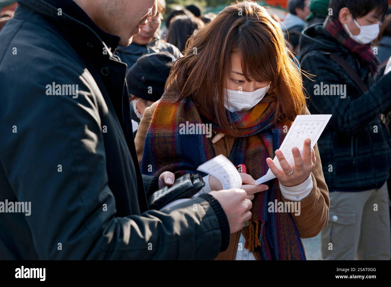 Persone che leggono il loro "omikuji" (oracolo di buona o cattiva sorte) durante la "Hatsumode" (visita al santuario di Capodanno) al santuario shintoista Heian Jingu a Kyoto, in Giappone Foto Stock