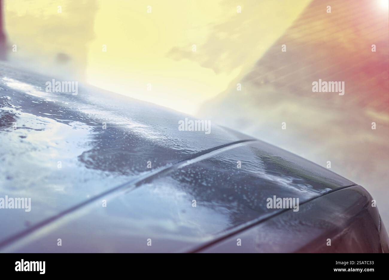 Superficie dell'auto con gocce d'acqua che riflettono la luce solare, creando colori vivaci Foto Stock