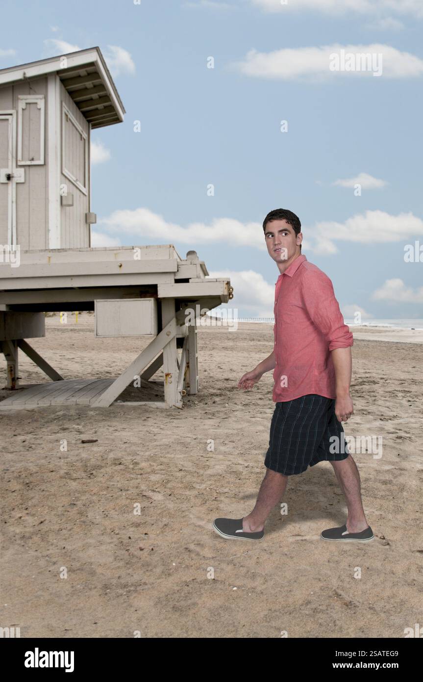 Bell'uomo che fa una lunga passeggiata sulla spiaggia Foto Stock