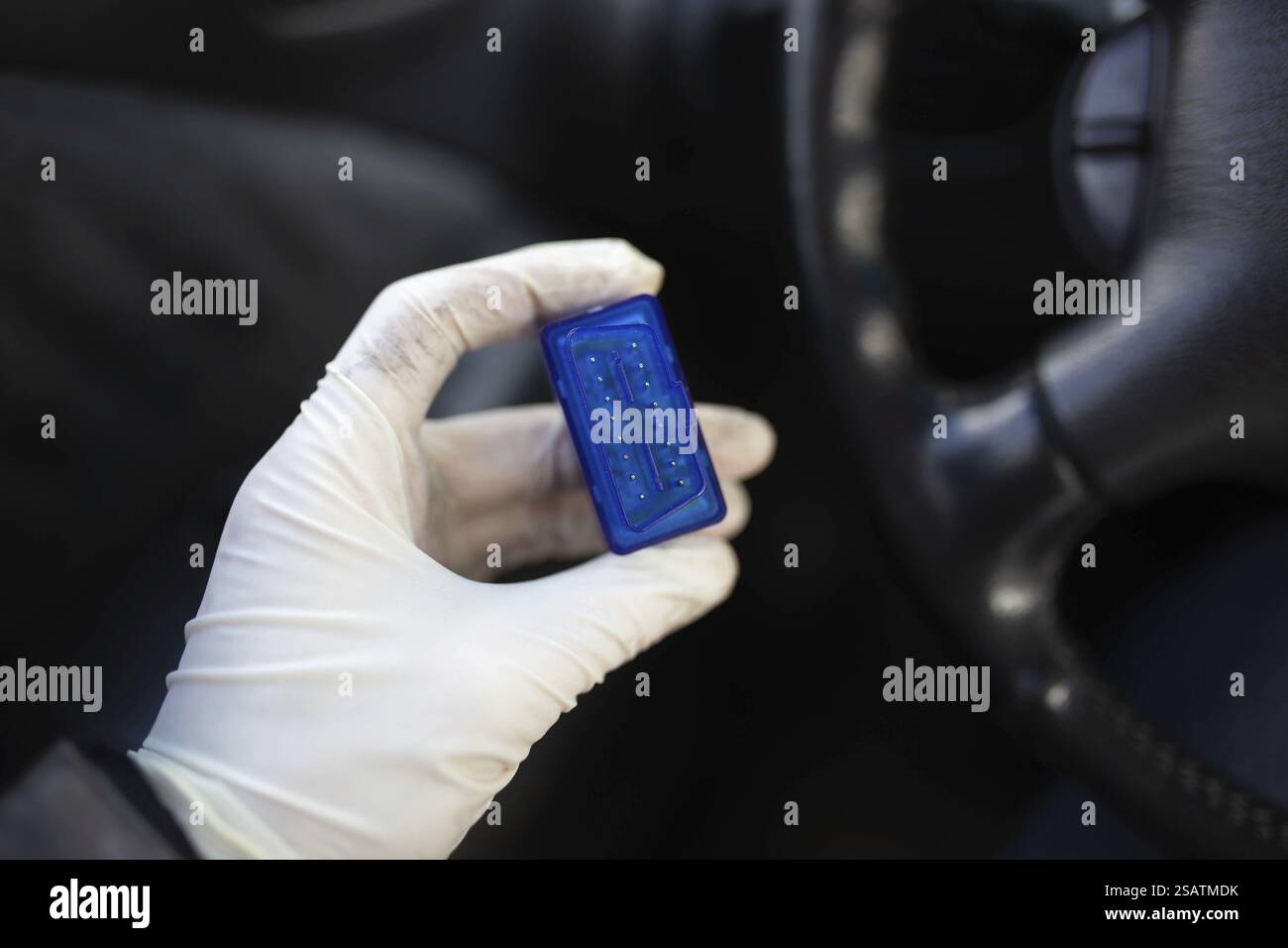Mano con guanti che reggono un chip blu all'interno dell'abitacolo Foto Stock