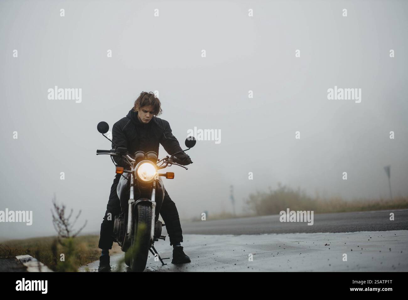 Una persona in moto percorre una strada nebbiosa, creando un senso di solitudine e avventura Foto Stock
