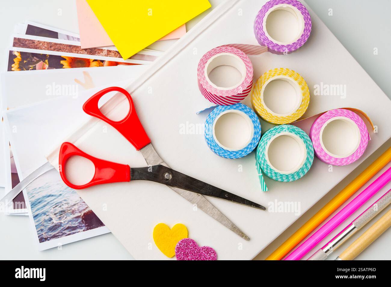 I materiali per la creazione si diffondono su un tavolo per progetti creativi con forbici, nastro washi e carta colorata Foto Stock