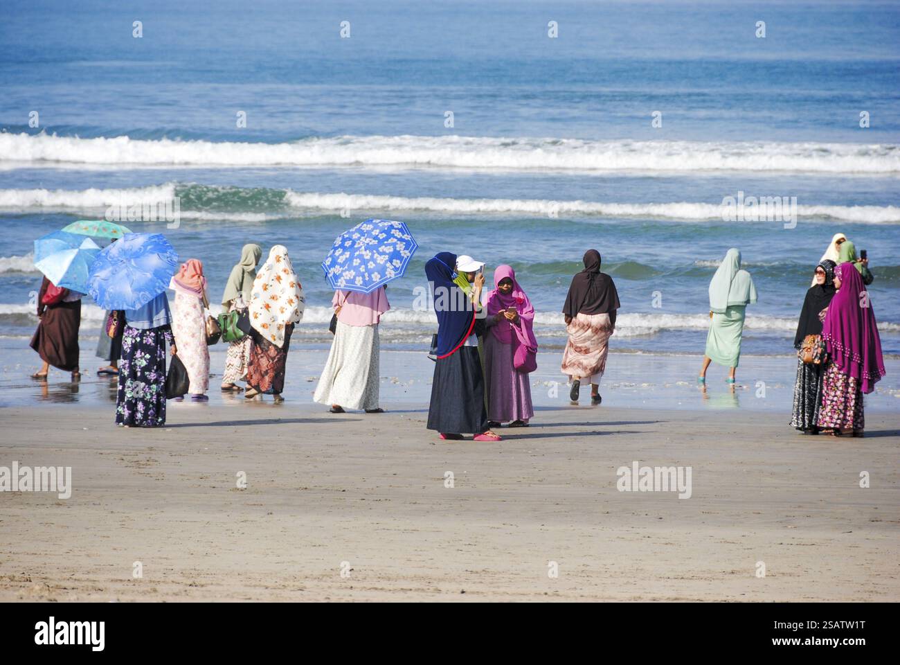 Donne che guardano il mare sulla spiaggia di Kuta, Bali, vestite con abiti tradizionali Foto Stock