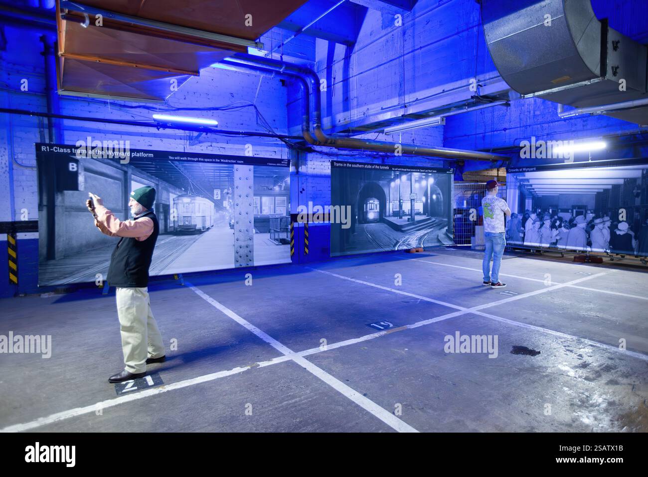 Persone nei vecchi tunnel abbandonati della stazione di Wynyard sotto Sydney, Australia, che guardano una mostra di foto storiche Foto Stock