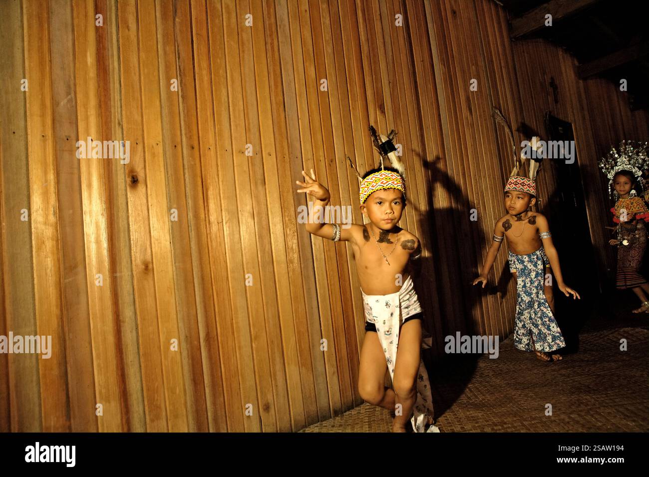 Bambini in abiti tradizionali che eseguono danza di benvenuto durante un evento di ecoturismo presso la casa di riposo della comunità tradizionale Dayak IBAN a Sungai Utik, Batu Lintang, Embaloh Hulu, Kapuas Hulu, West Kalimantan, Indonesia. Secondo la legge indonesiana sulla protezione dell'infanzia, numero 35/2014, il gruppo di bambini che dovrebbero ricevere una protezione speciale sono minoranze e bambini isolati; questo include i bambini indigeni che vivono per lo più in aree remote, ha scritto un team di scienziati guidati da mira Azzasyofia (Facoltà di istruzione e lavoro sociale, l'Università di Auckland). Foto Stock