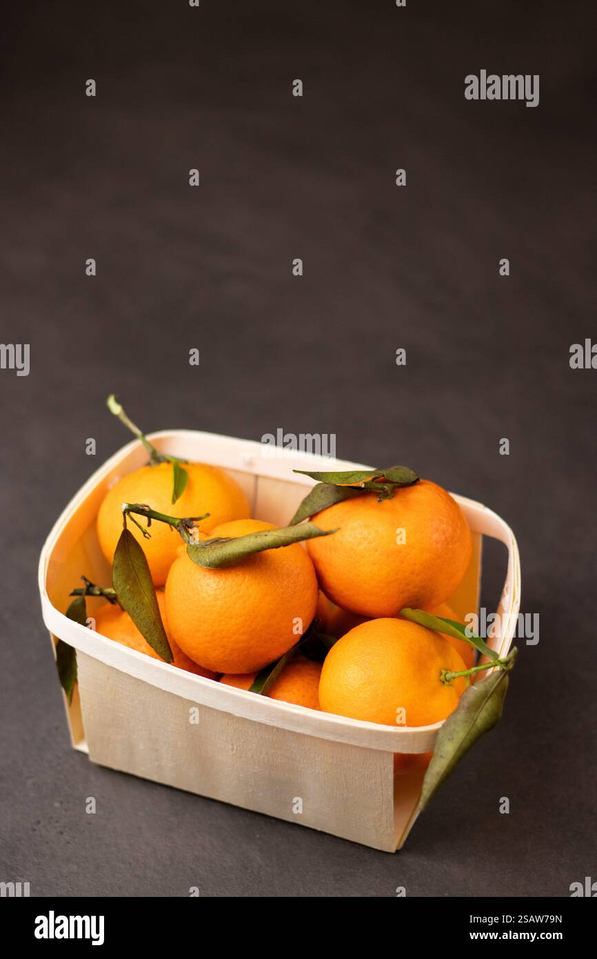 Primo piano di frutta mandarina in una scatola di legno su sfondo grigio Foto Stock