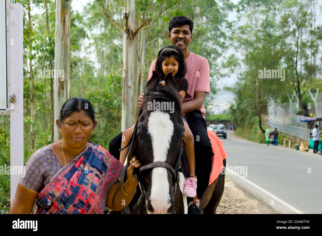Questa immagine cattura una famiglia indiana che cavalca un cavallo in una strada trafficata Foto Stock