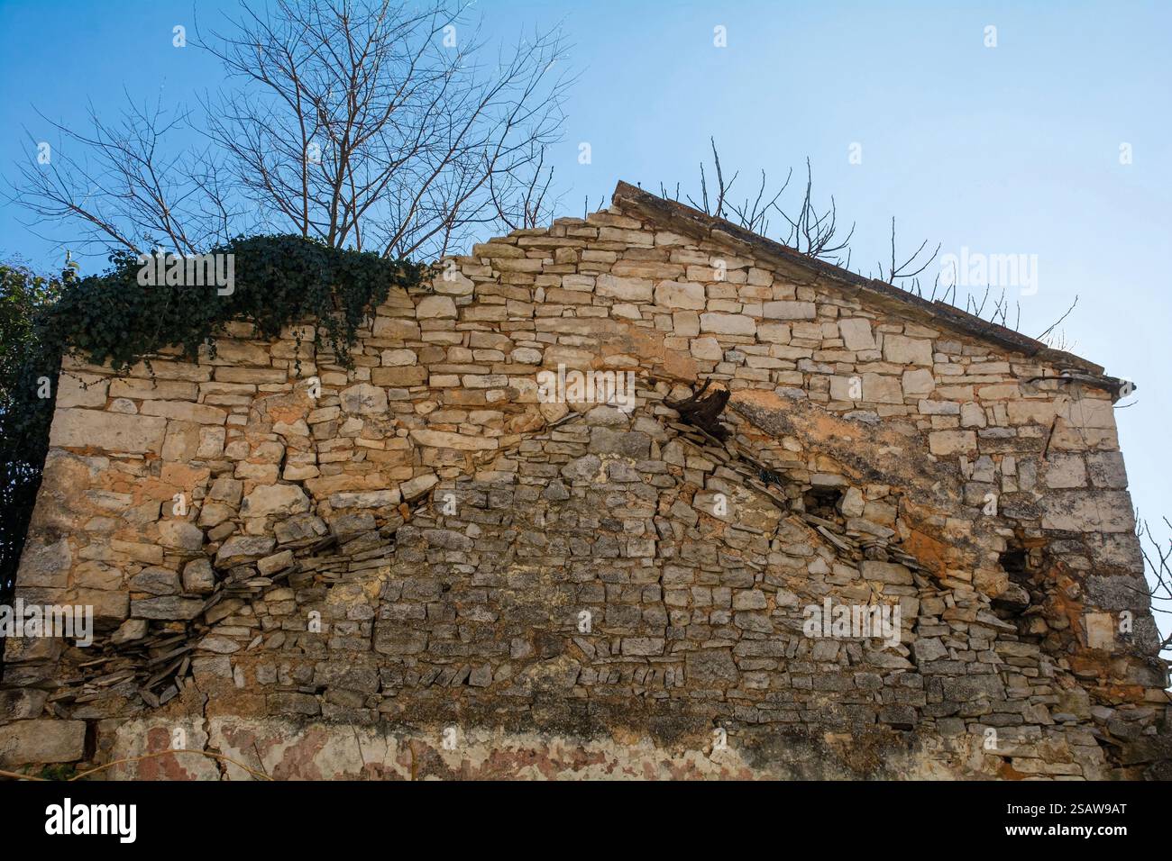 Lato di una vecchia casa in pietra che mostra il profilo del tetto a timpano del precedente edificio in pietra a 1 piano, diversi stili e allineamenti in muratura. Svetvincenat, Croazia Foto Stock