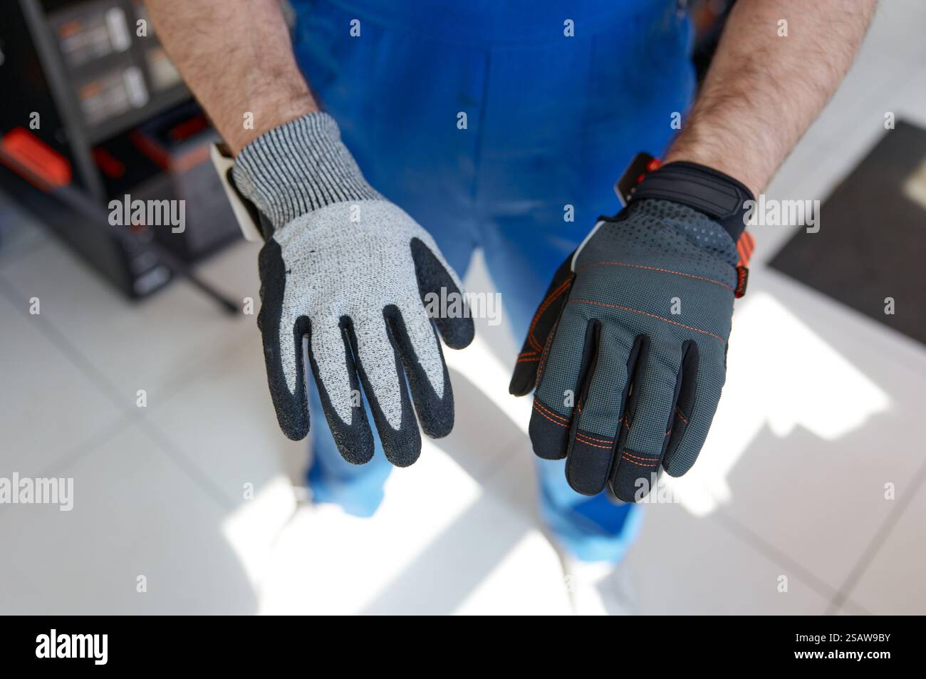 Il proprietario di un negozio di ferramenta indossa guanti da costruzione Foto Stock