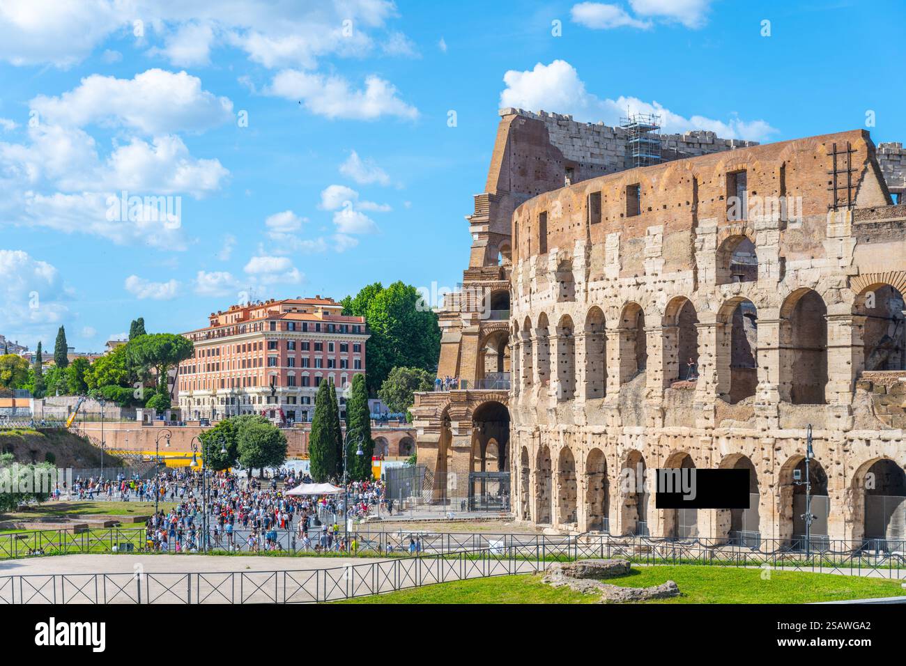 La folla si raduna vicino al Colosseo di Roma, in Italia, sotto un cielo azzurro. Questo iconico monumento mostra l'antica architettura e attrae turisti tutto l'anno con il suo significato storico. Foto Stock