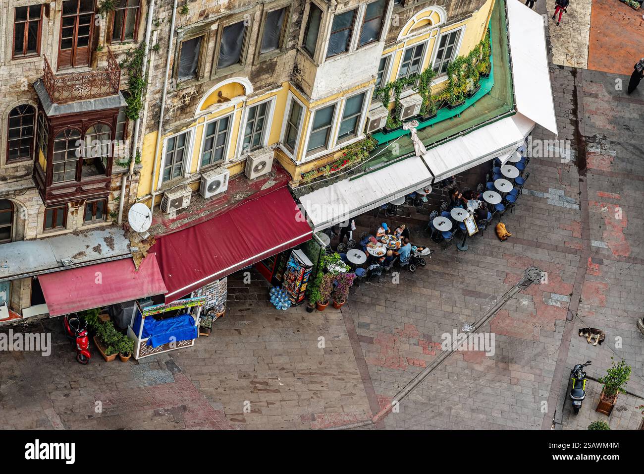 Un vivace caffè urbano con clienti, circondato da architettura storica e posti a sedere aperti. Un'affascinante miscela di atmosfera europea e attività quotidiane Foto Stock