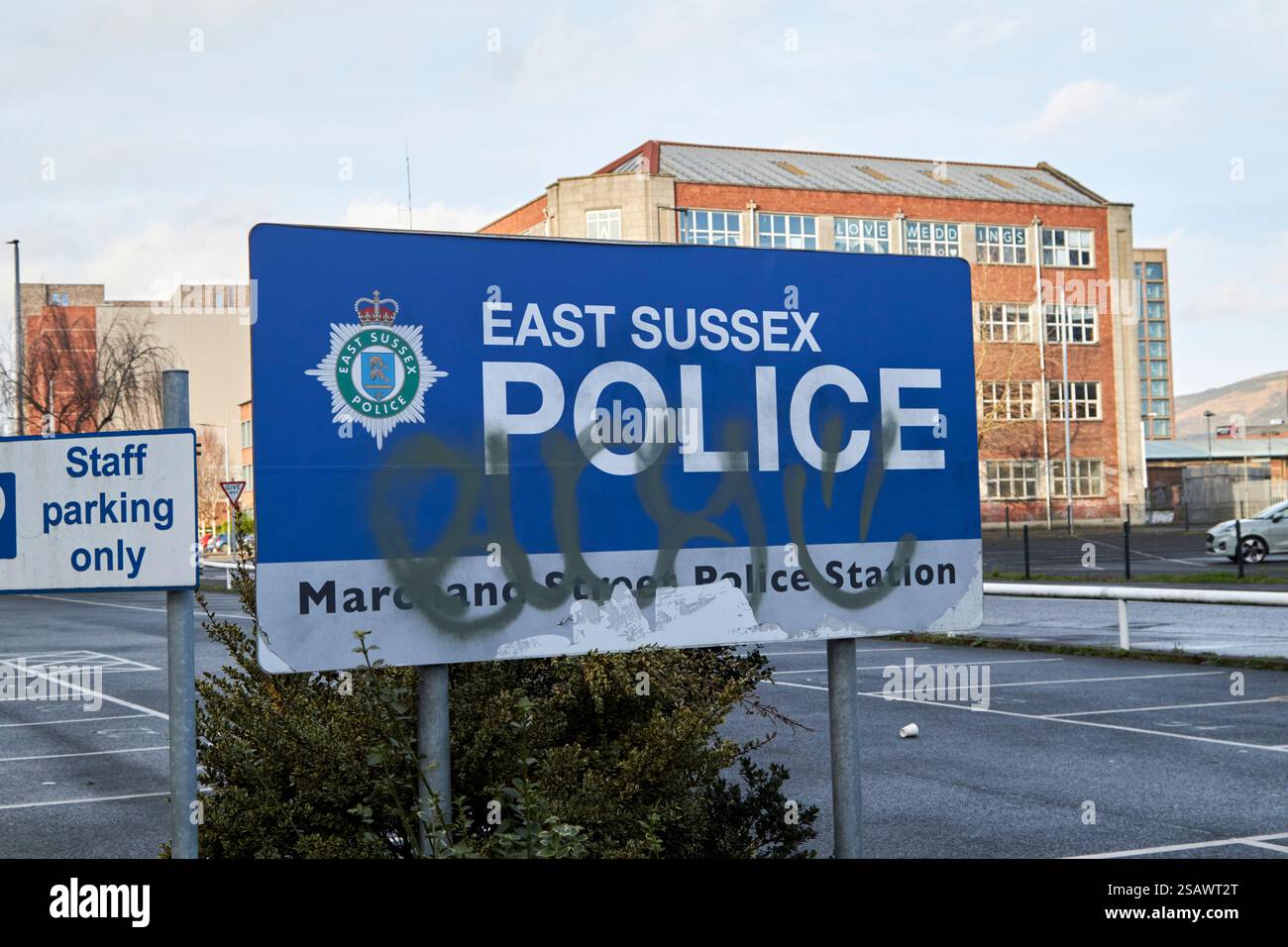 Graffiti coprirono il cartello per la stazione di polizia immaginaria del sussex est marchand Street utilizzata nella serie tv della BBC Showtrial belfast, irlanda del Nord, regno unito Foto Stock