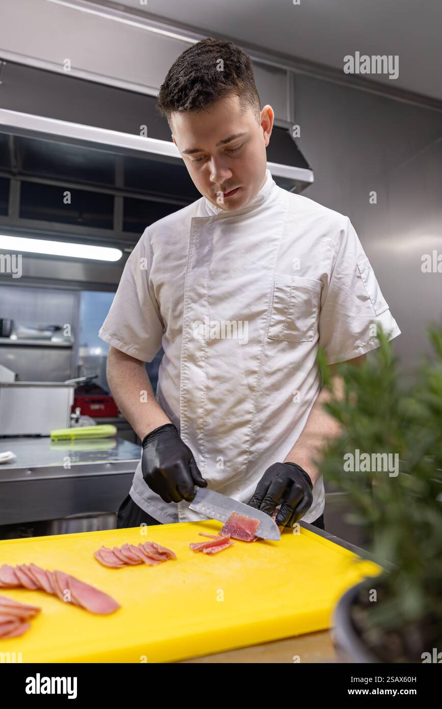 Chef professionista affettare tonno su tagliere giallo nella cucina del ristorante Foto Stock