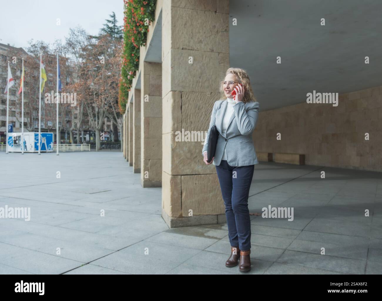 Donna d'affari che sorride mentre parla al telefono Foto Stock
