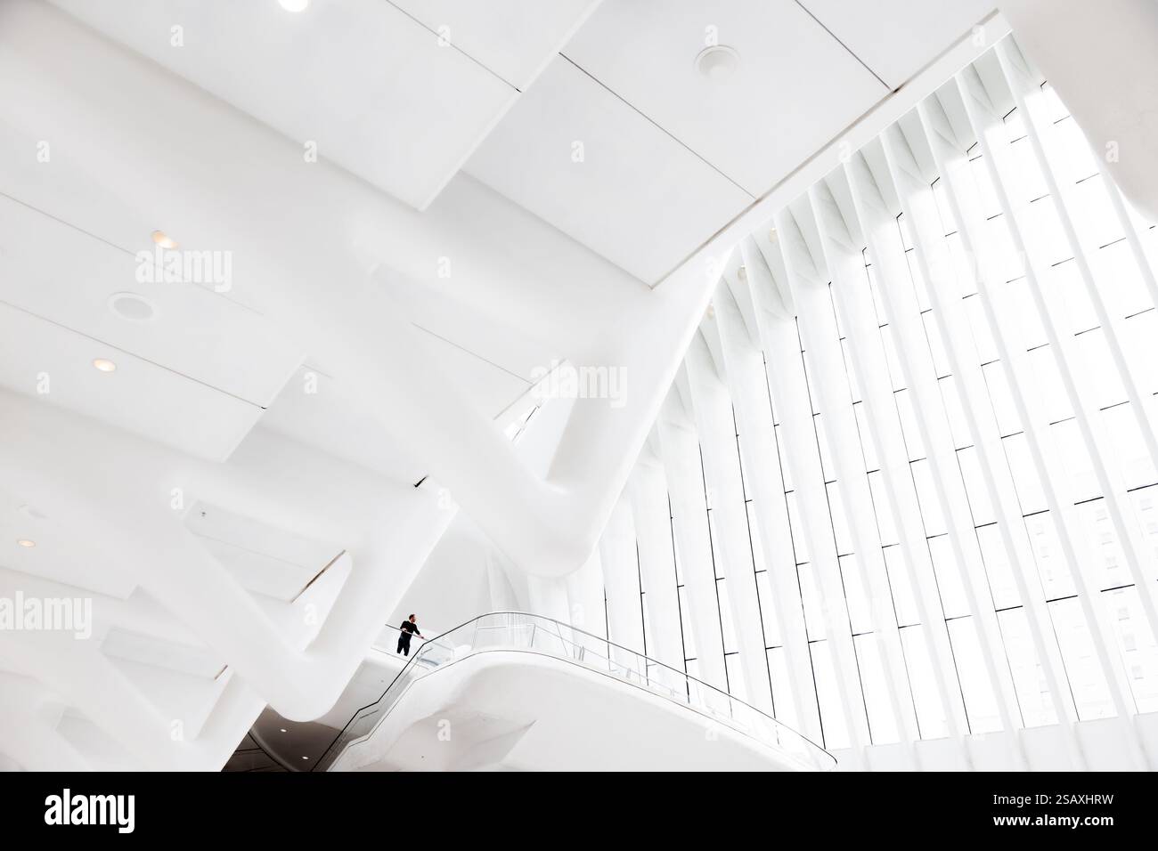 Un interno grafico e luminoso di colore bianco del centro commerciale Westfield presso il World Trade Center di New York, che incornicia una figura solitaria su un balcone distante. Foto Stock