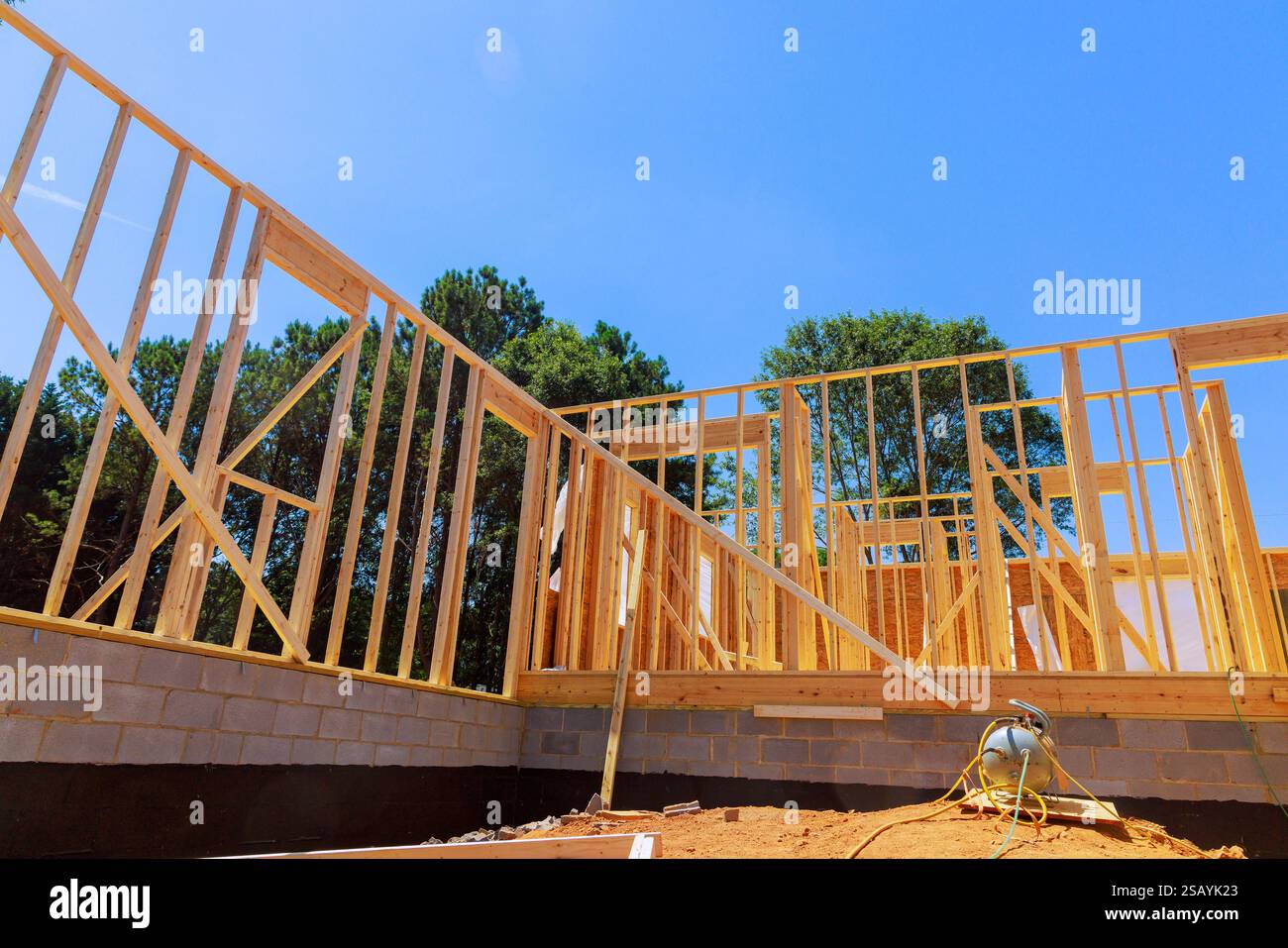 I costruttori stanno lavorando per incorniciare la nuova casa con travi di legno nell'area residenziale nel quartiere suburbano Foto Stock