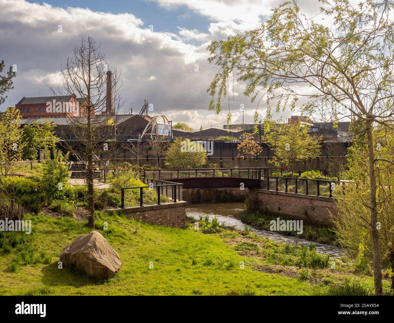 Il fiume Medlock scorre attraverso Mayfield Park, l'area Ardwick Green di Manchester in lontananza. Foto Stock